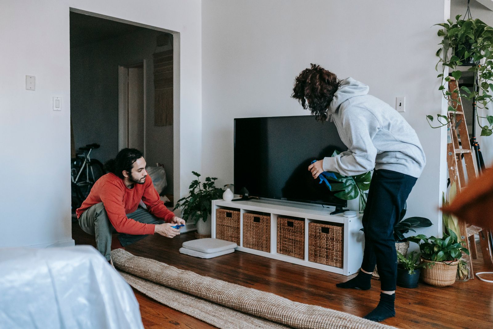 A couple organizing their living space with modern interior design elements and household items.
