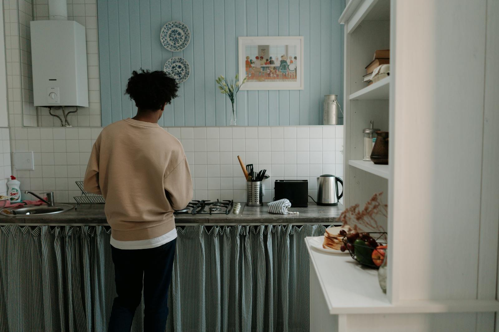 A man with afro hair cooking alone in a stylish, serene kitchen setting.