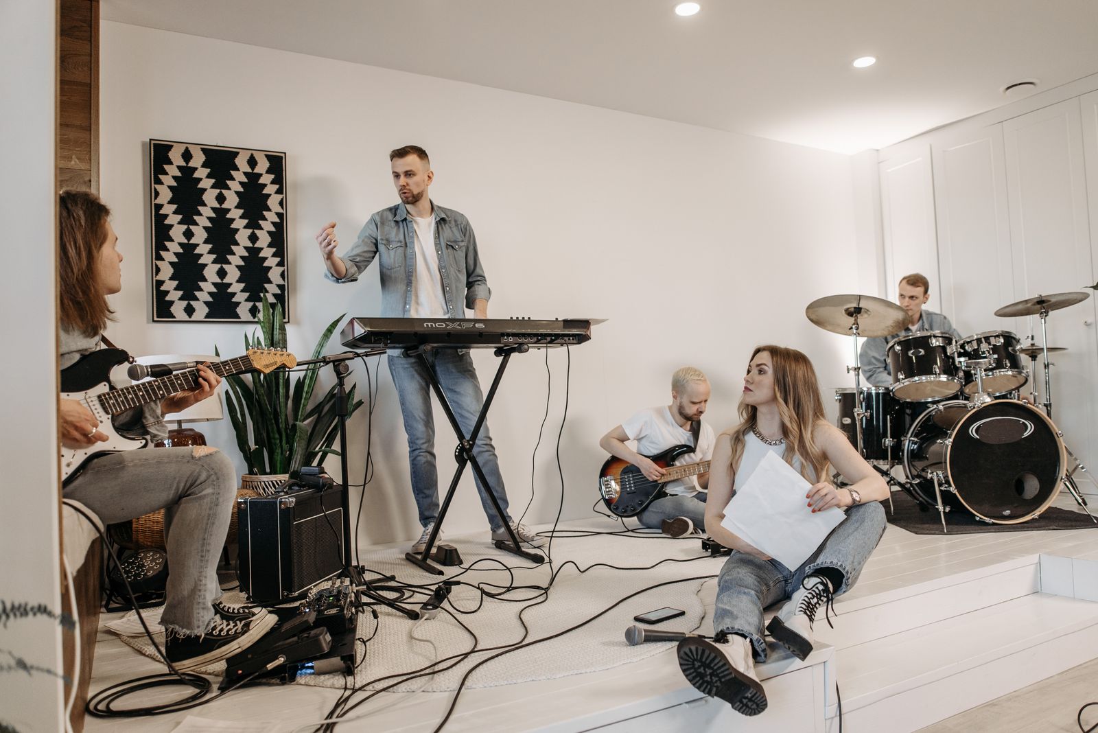 Group of young musicians practicing with instruments in a modern studio setting.
