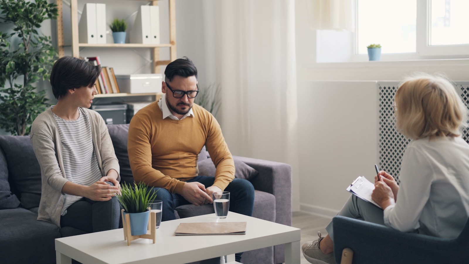 a man and woman sitting on a couch talking to each other