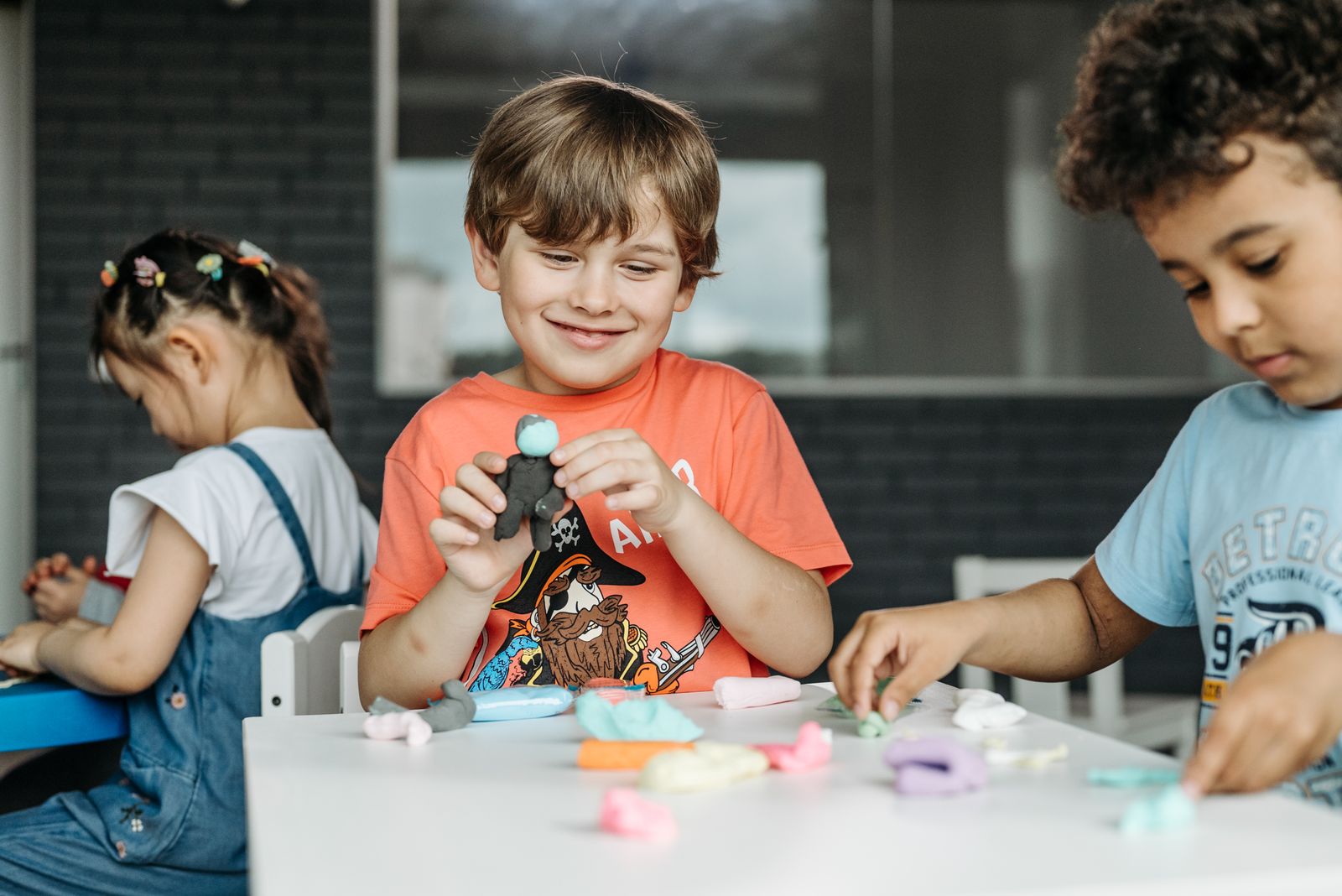 Children engaged in creative play with colorful clay indoors, expressing joy and imagination.