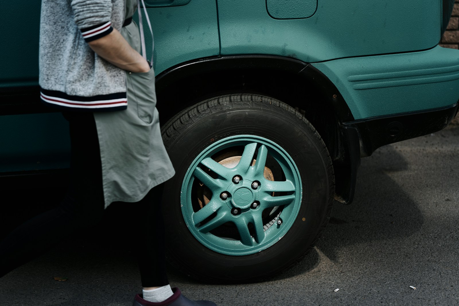 A woman standing next to a green van