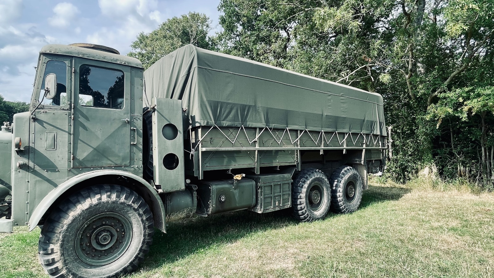A vintage olive green military truck with a canvas cover