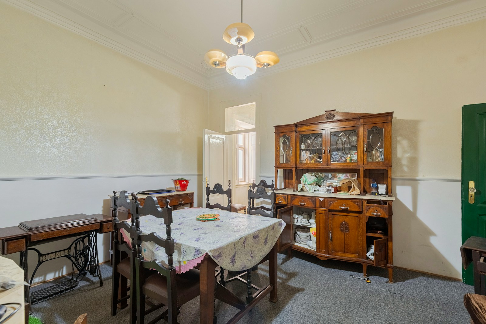 Dining room with vintage furniture and a sewing machine.