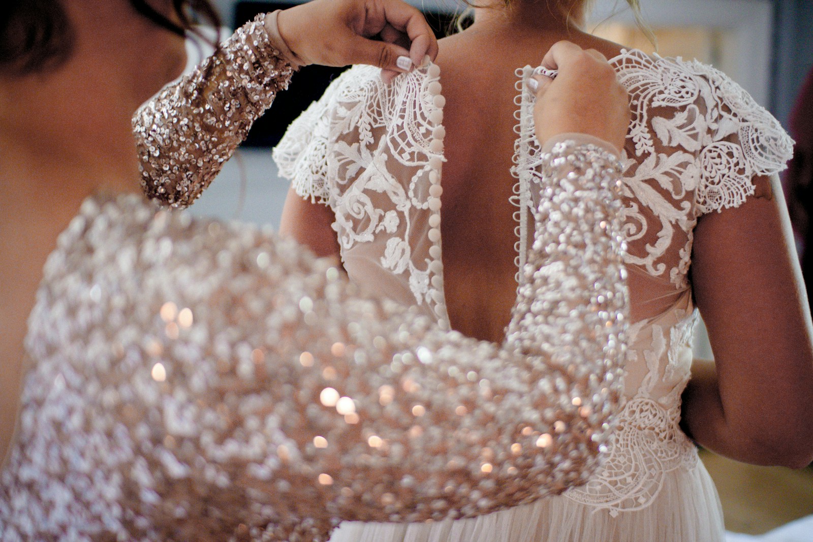 Someone is zipping up the bride's dress.