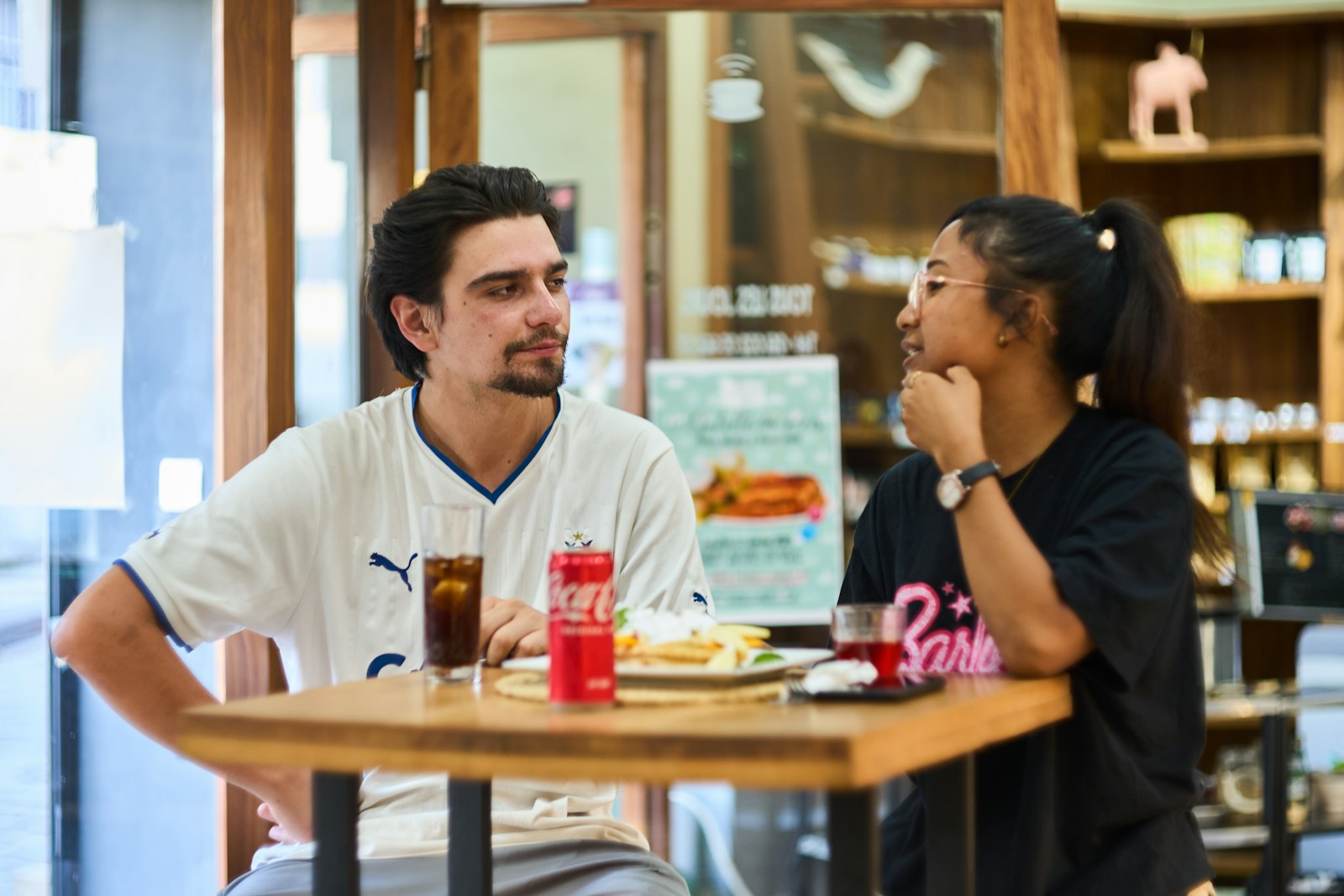 Two people are chatting and eating at a cafe.