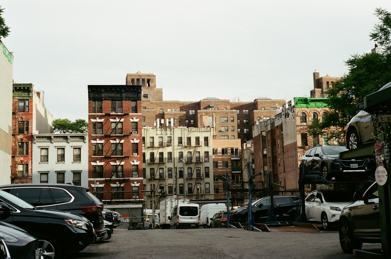City street with parked cars and residential buildings.