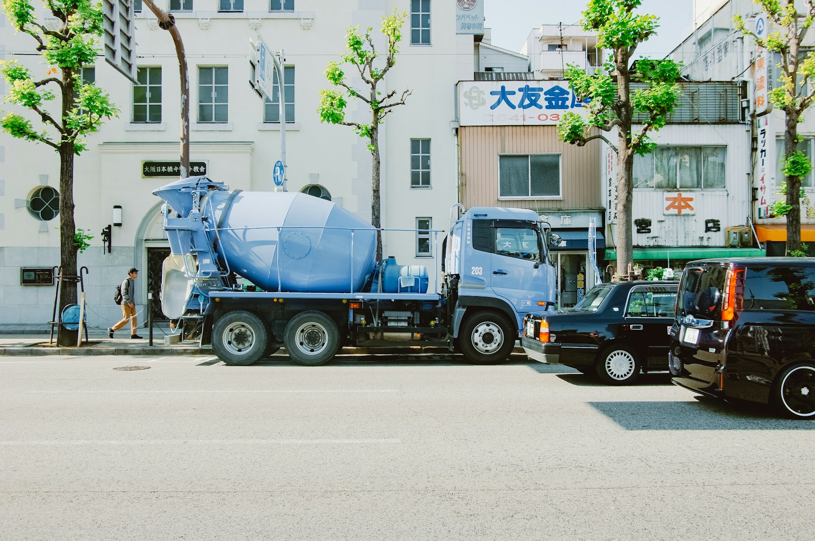 A light blue cement truck parked on street.