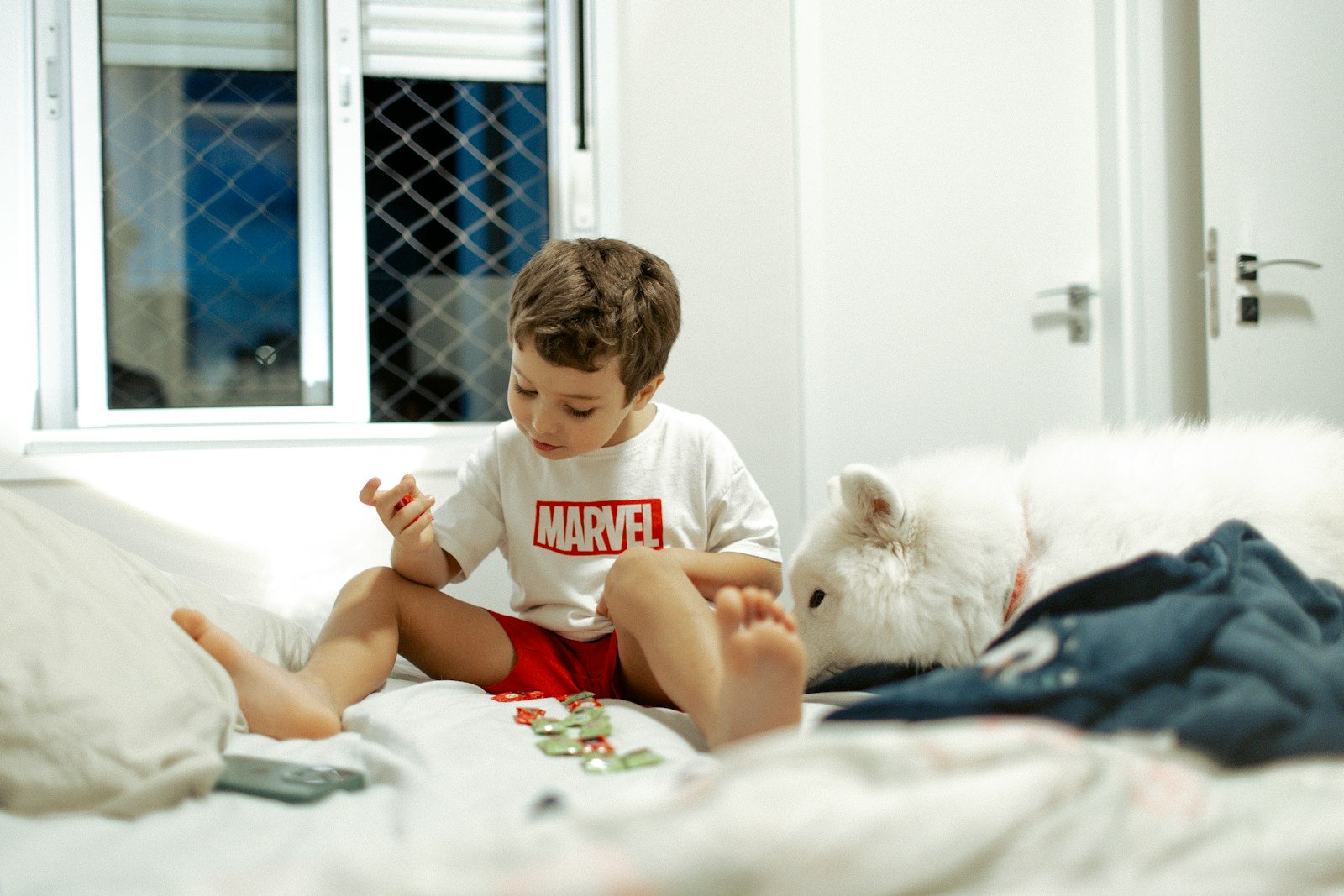 Young boy playing with toys on a bed.