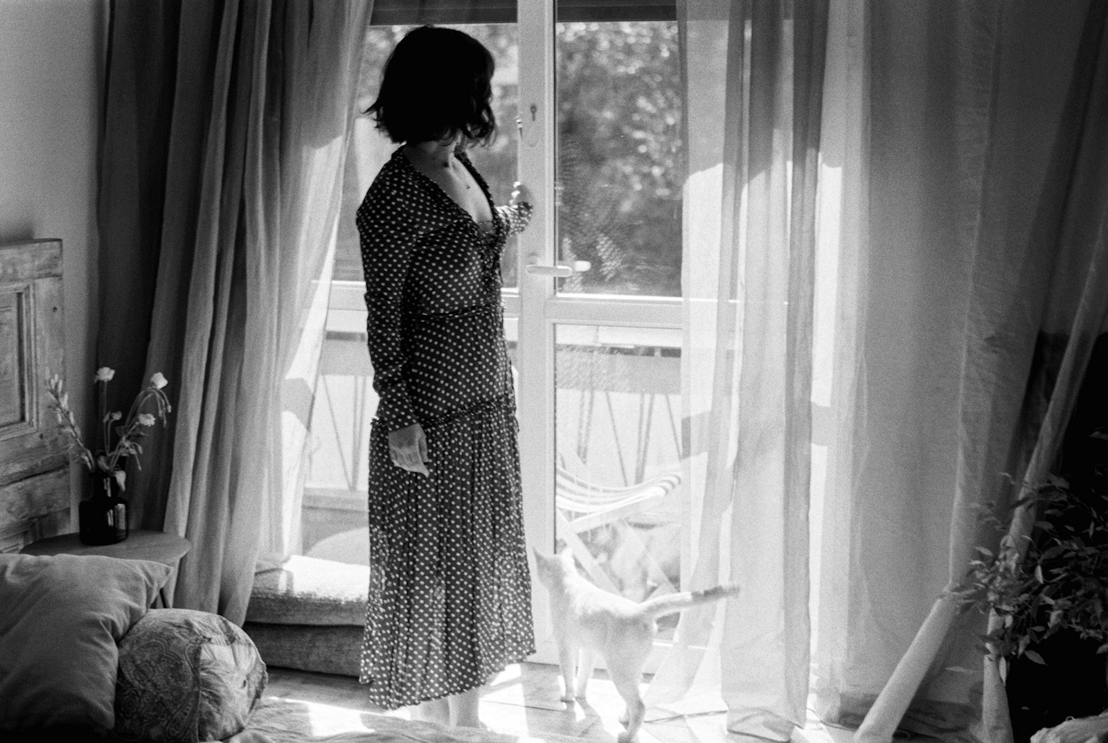 a woman standing in front of a window next to a cat
