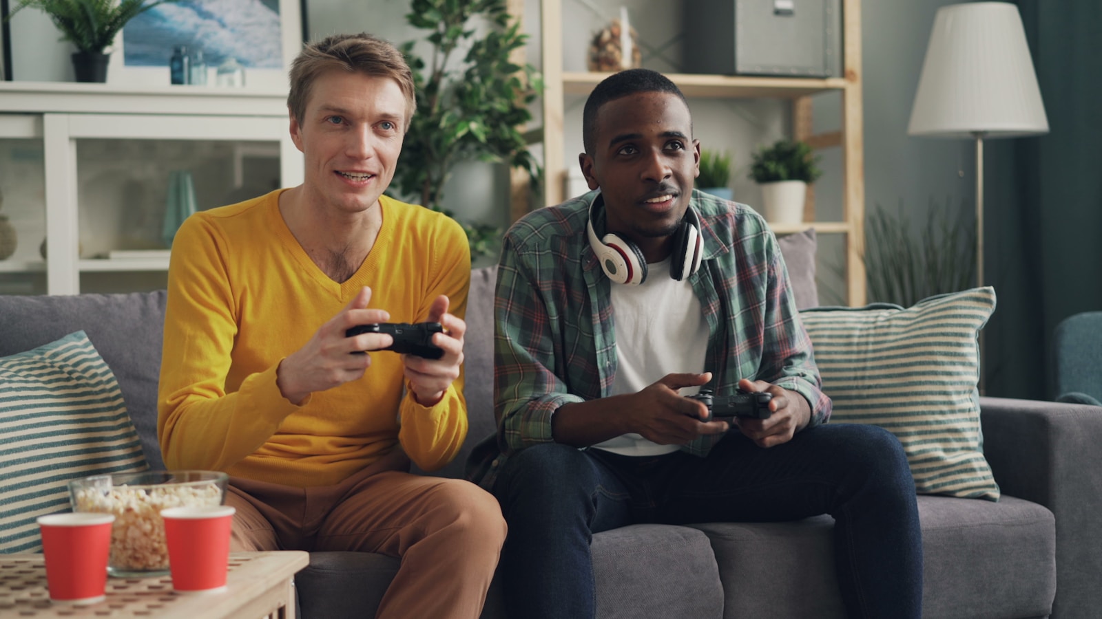 two men sitting on a couch playing video games