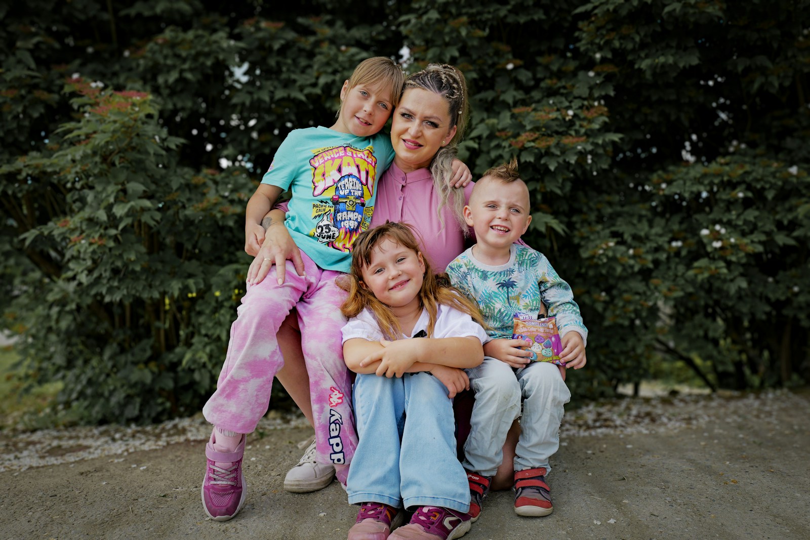 A woman poses with three smiling children outdoors.