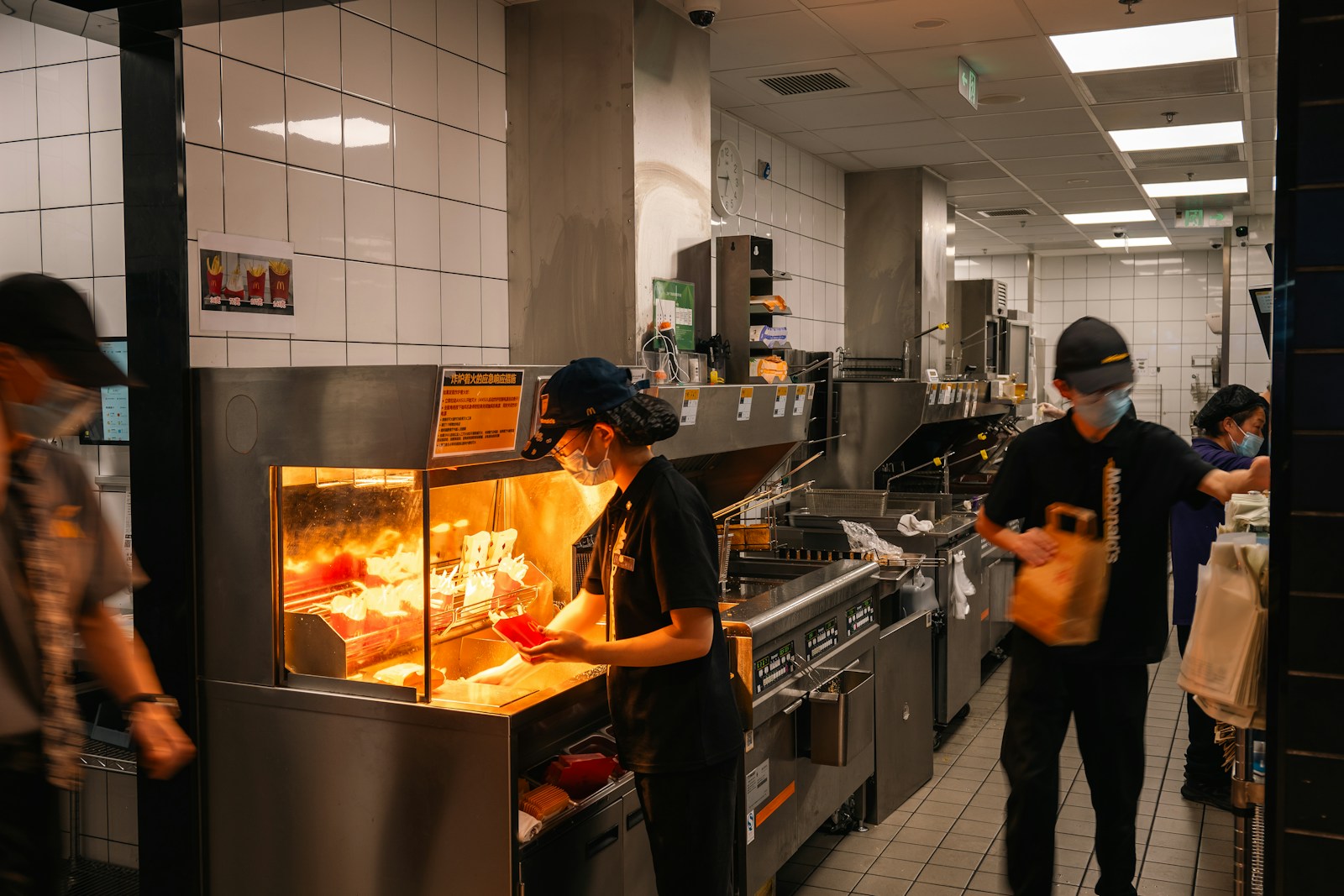 Workers preparing food in a busy restaurant kitchen.