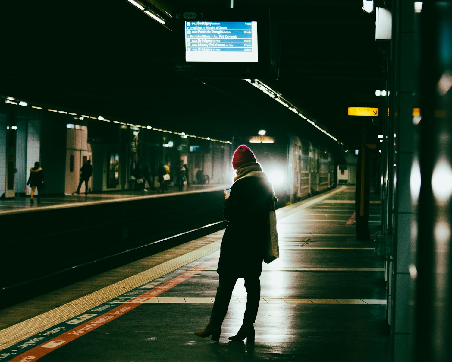 a person standing in a train station waiting for a train