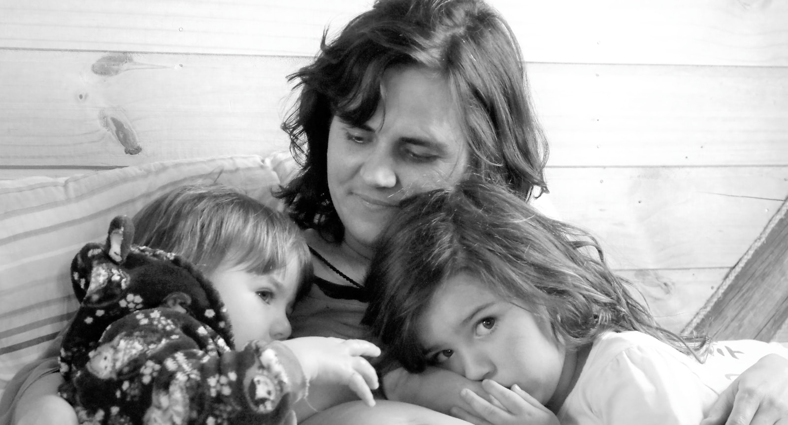 A woman and two small children laying on a bed