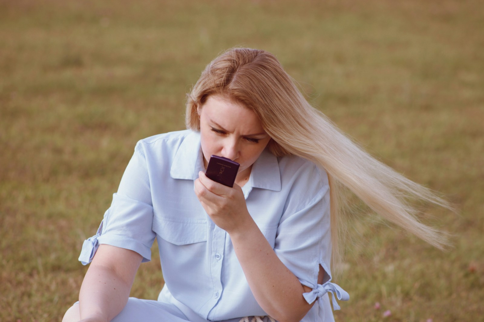 a woman sitting on the ground holding a cell phone