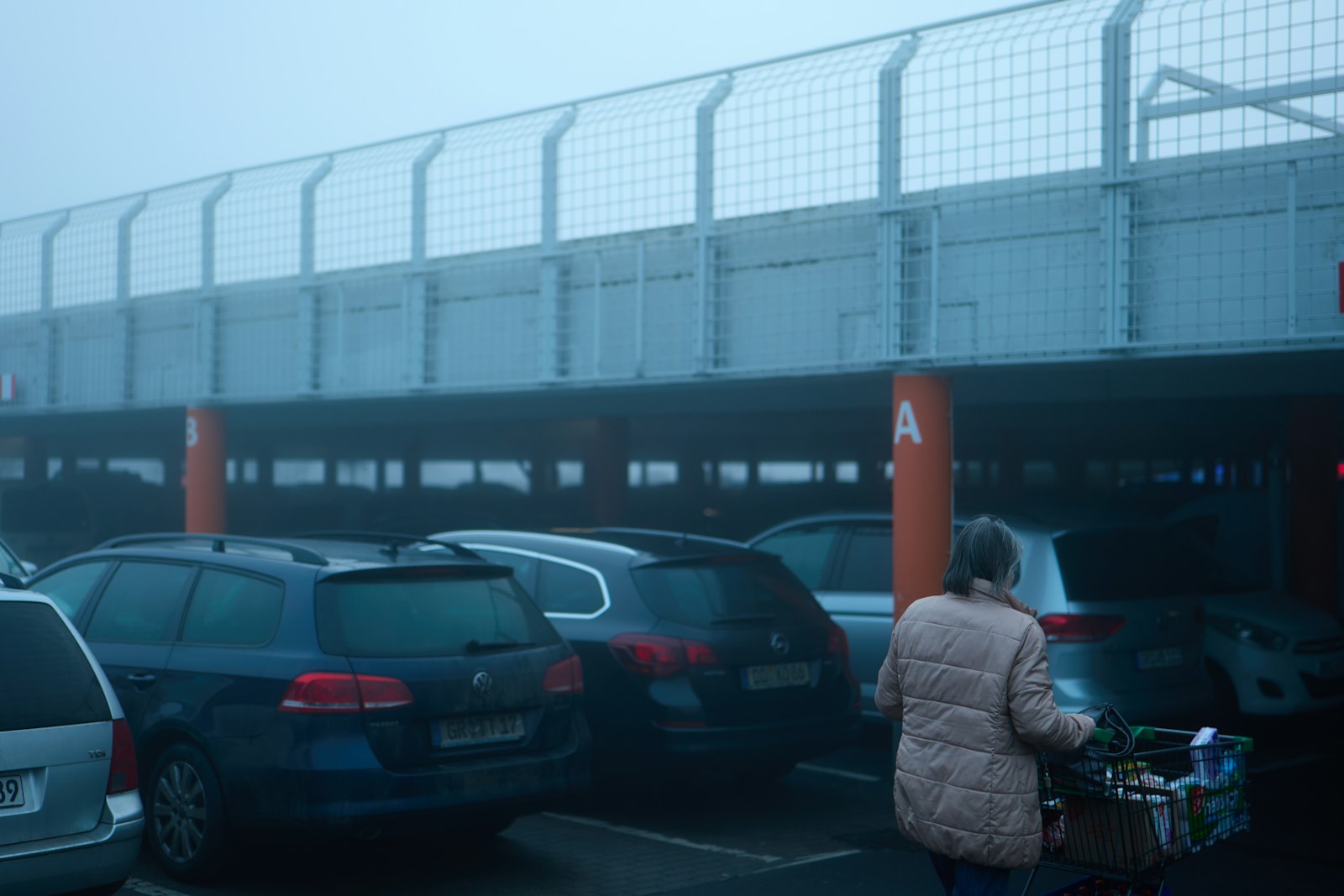 Woman pushing cart in foggy parking garage