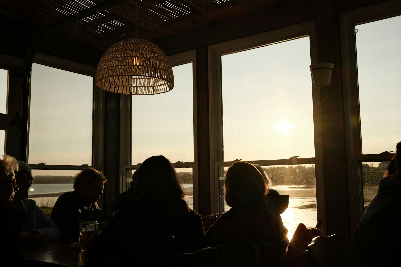Silhouettes of people watching sunset over water