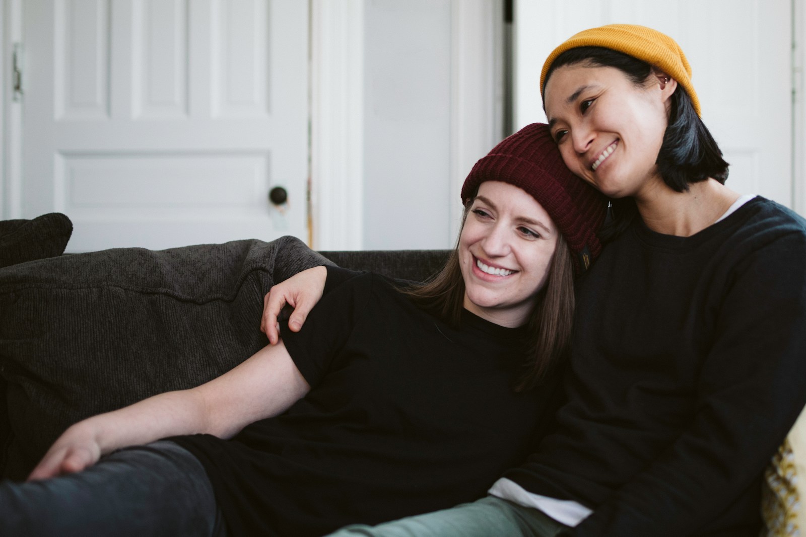 woman in black long sleeve shirt sitting beside woman in red knit cap