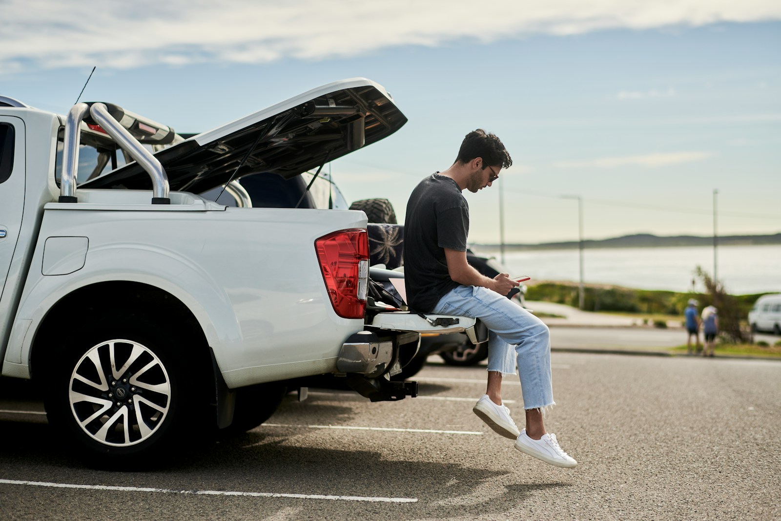 man sitting on car looking at phone