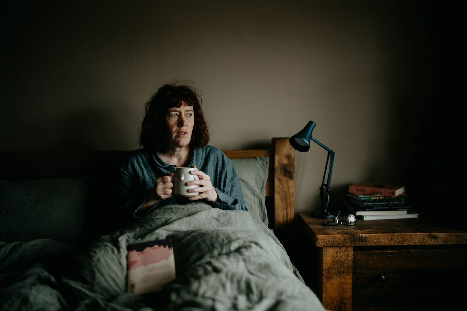 a woman sitting on a bed holding a cup of coffee
