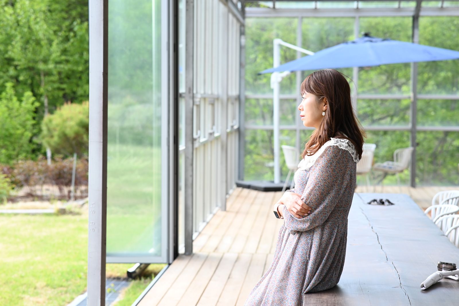 A serene moment of a woman enjoying the view from a porch on a sunny day, epitomizing relaxation.