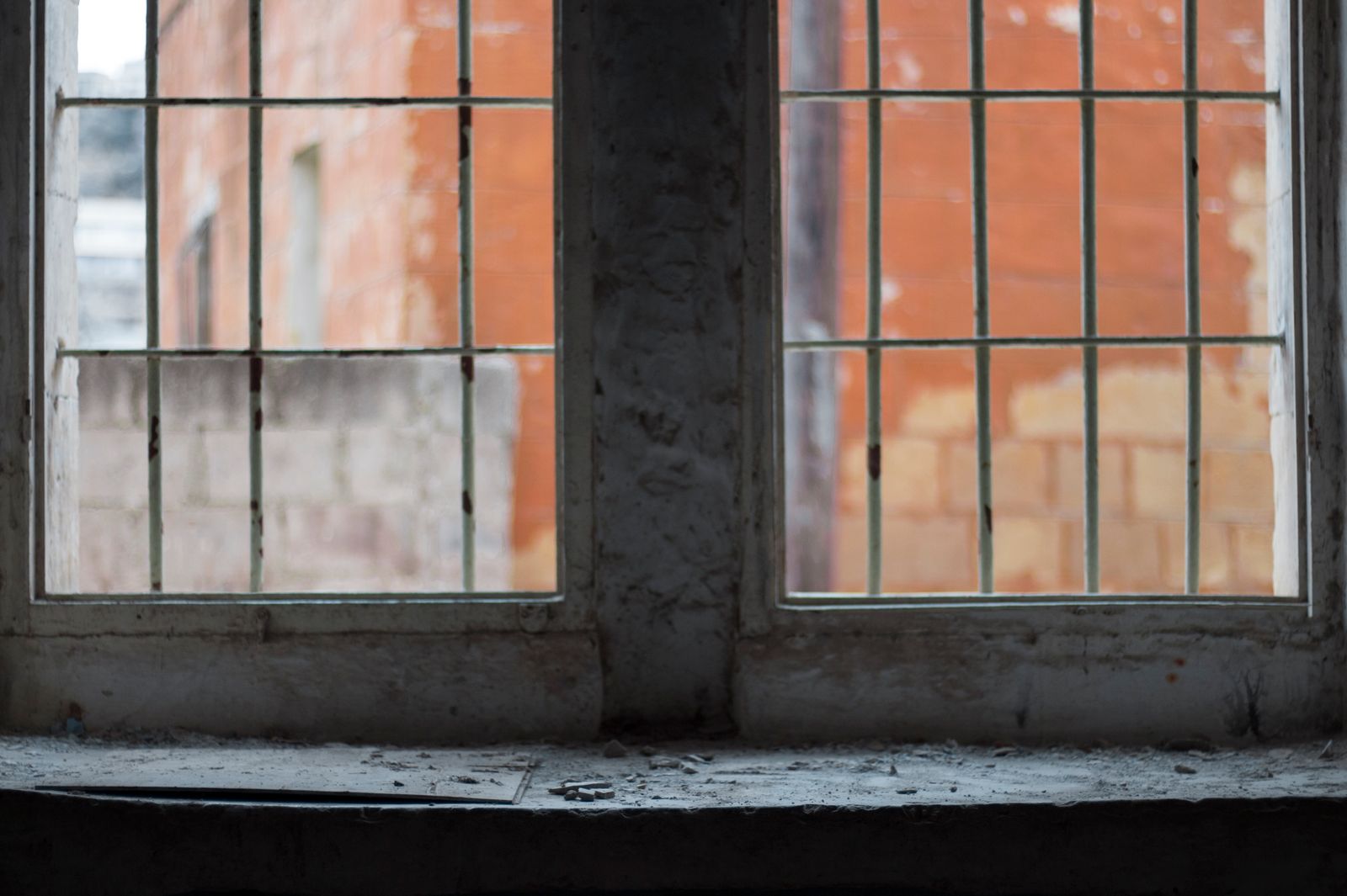 View through a rustic window of an abandoned building revealing aged brick walls.