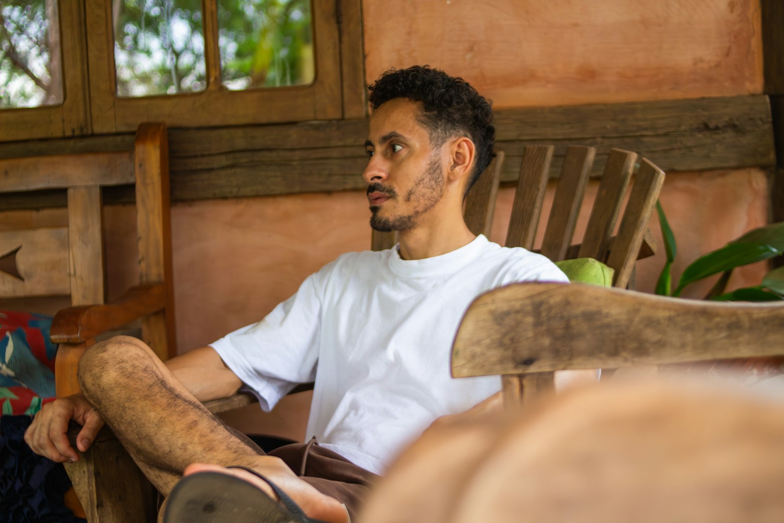 A man with a beard sits in a wooden chair.