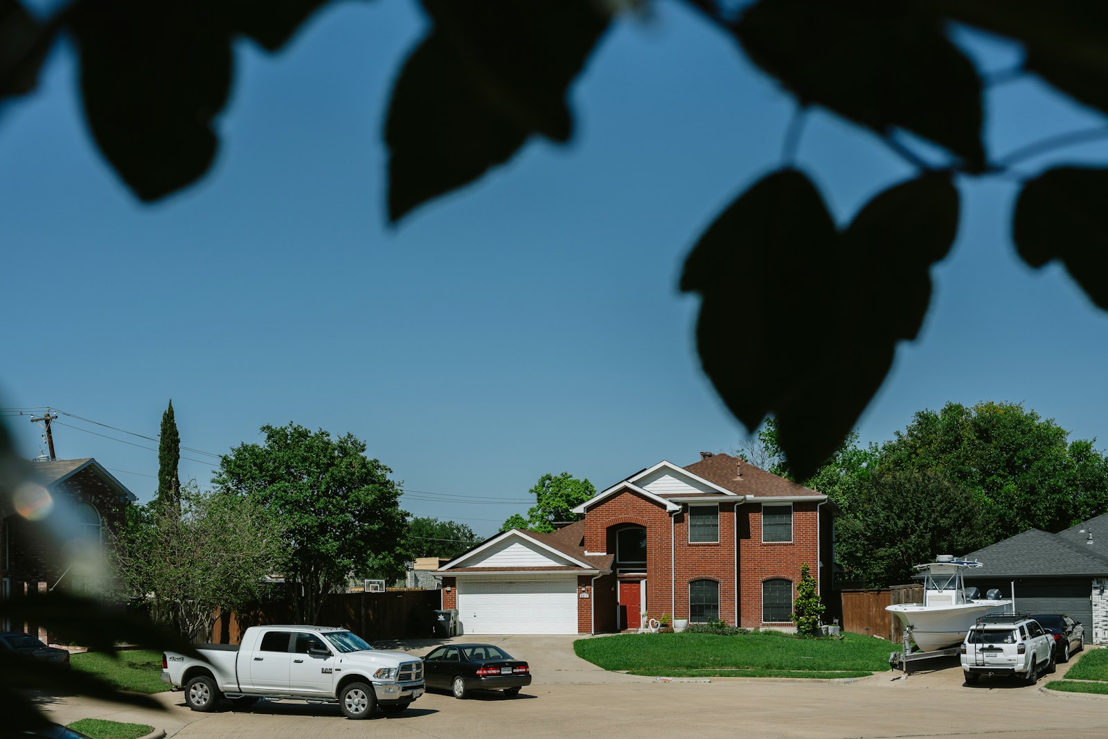 Brick house with cars in the driveway.