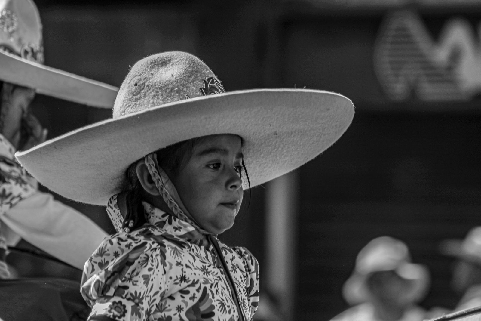 A young girl in a sombrero participates in a cultural celebration, showcasing Mexican traditions.