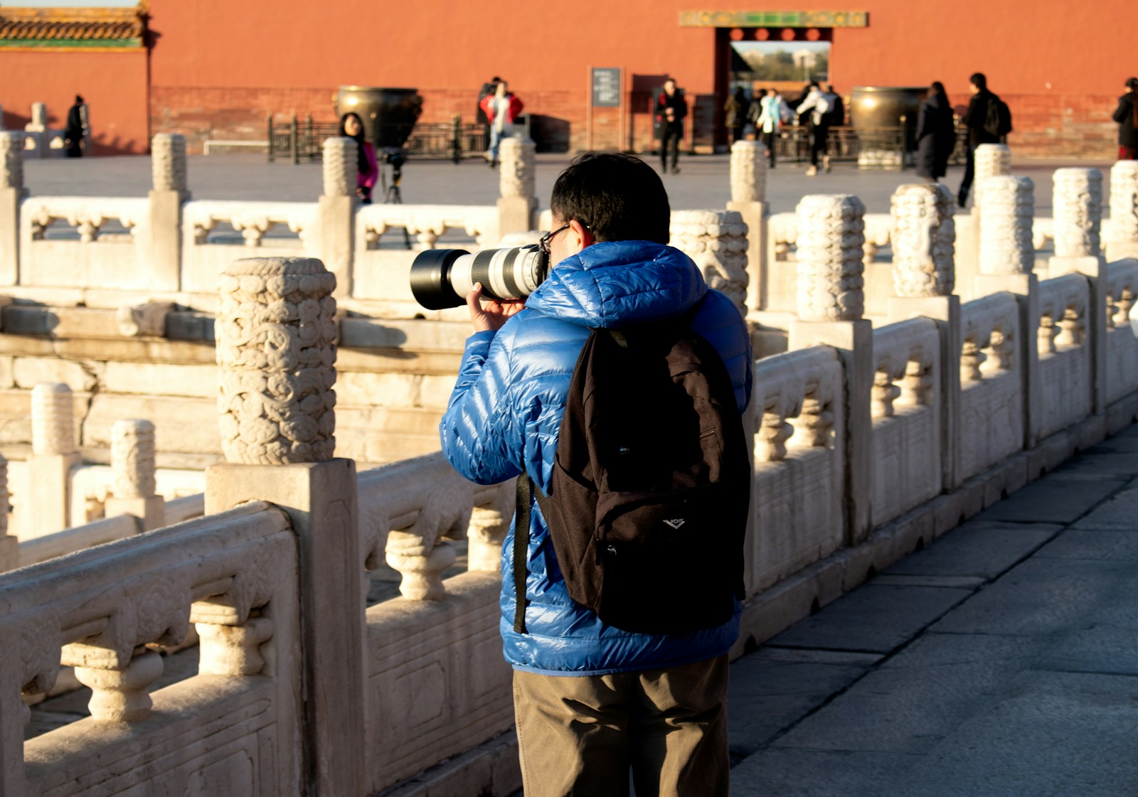 man in blue jacket and brown pants carrying black backpack