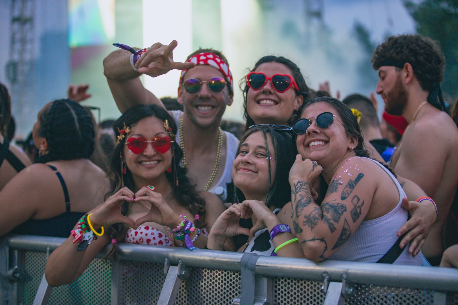 Joyful group of friends enjoying an outdoor music festival with colorful accessories and tattoos.