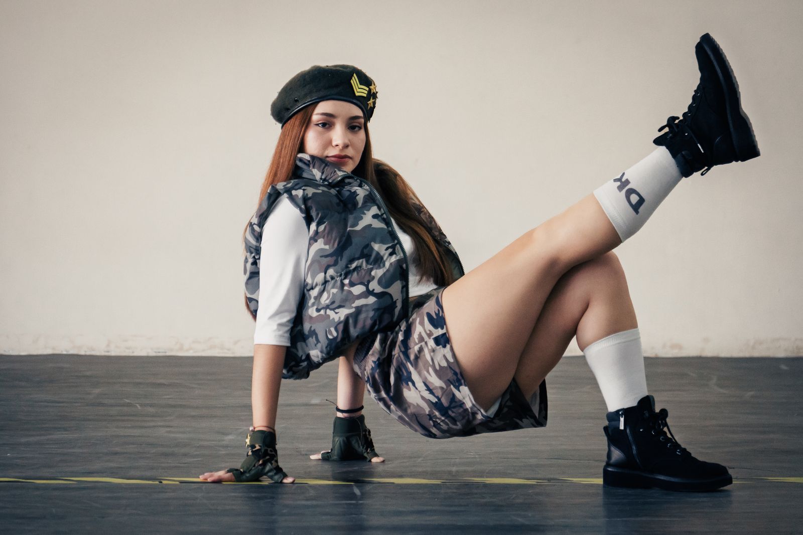 Fashionable woman in military-inspired outfit posing outdoors, showcasing urban style trends.