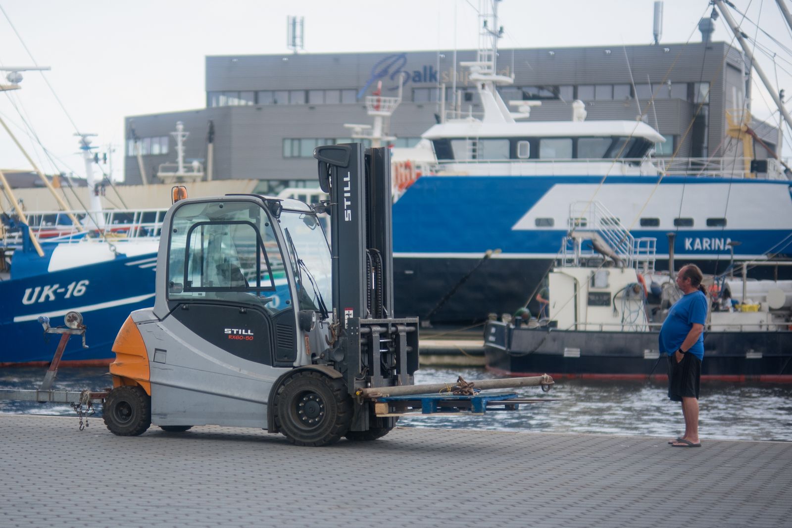Forklift operating in Urk harbor, Flevoland with ships in the background, urban scenery.