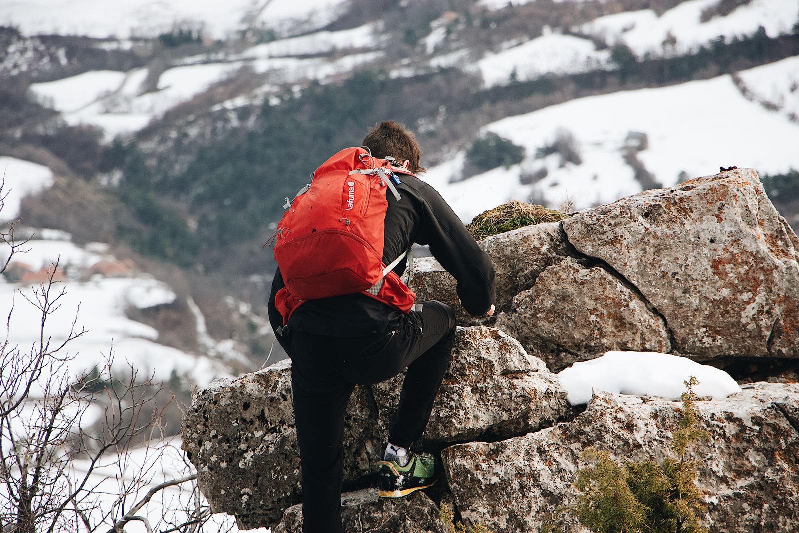 A person climbing rocky terrain with snow, enjoying a winter adventure outdoors.