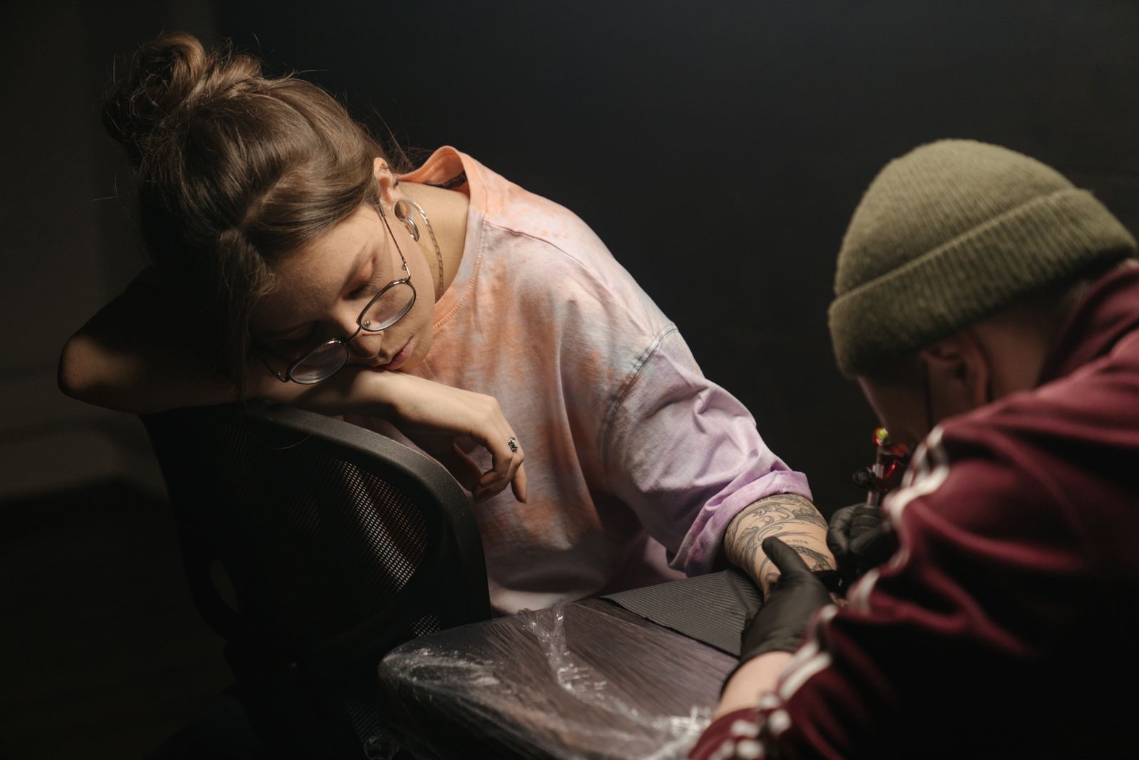 A woman patiently receiving a tattoo in a cozy, artistic tattoo studio.
