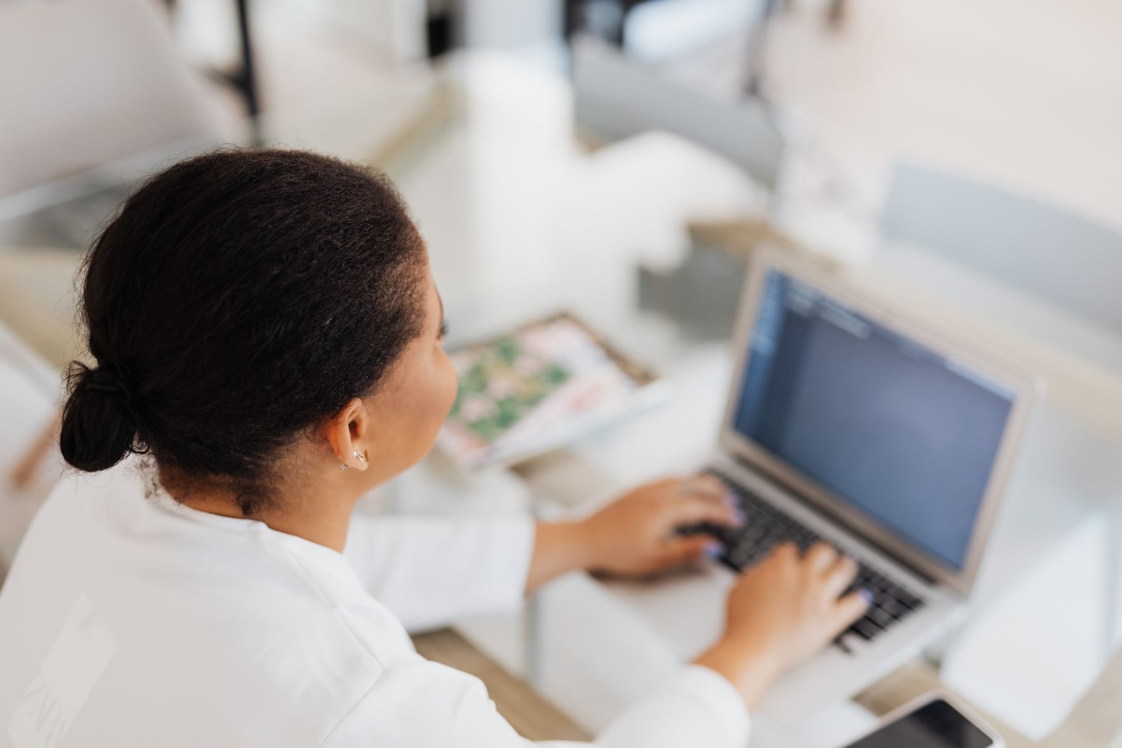 Black woman working on a laptop in a modern indoor office environment.