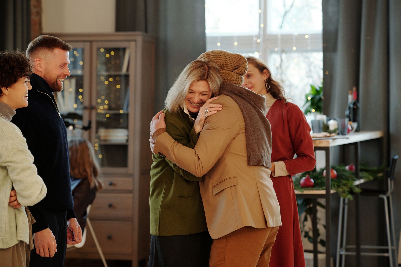 Family members embracing warmly at a festive indoor gathering, spreading holiday cheer.