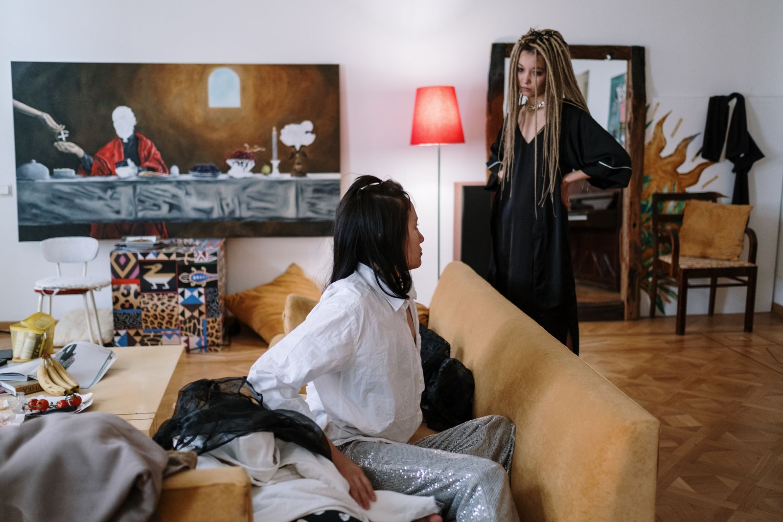 Two women engage in conversation in a creatively designed living room with striking art.