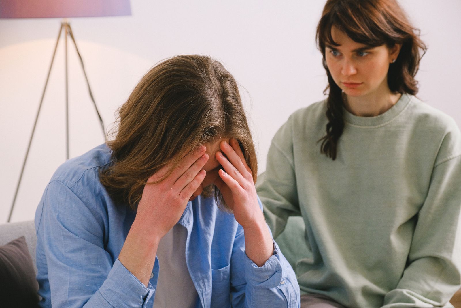 Crop woman watching on tired sad female with hands on forehead in modern studio in daytime