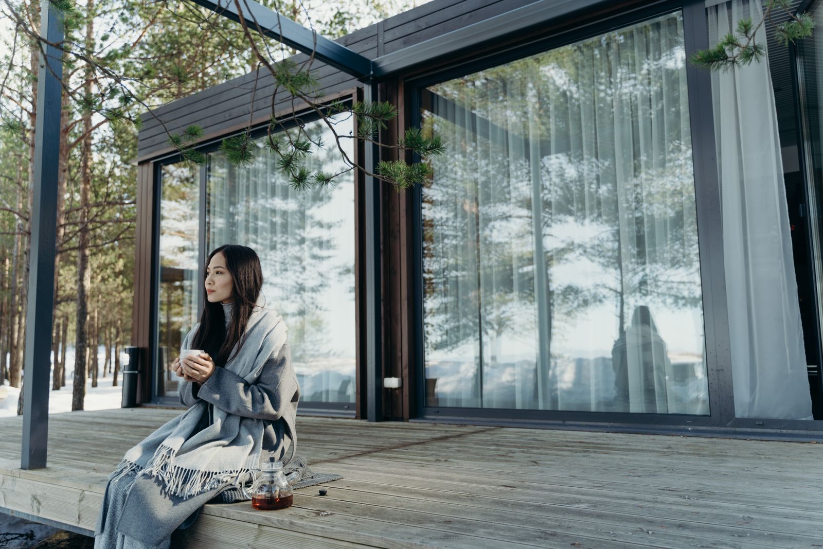 Asian woman enjoying a hot drink on a peaceful winter morning outdoors.