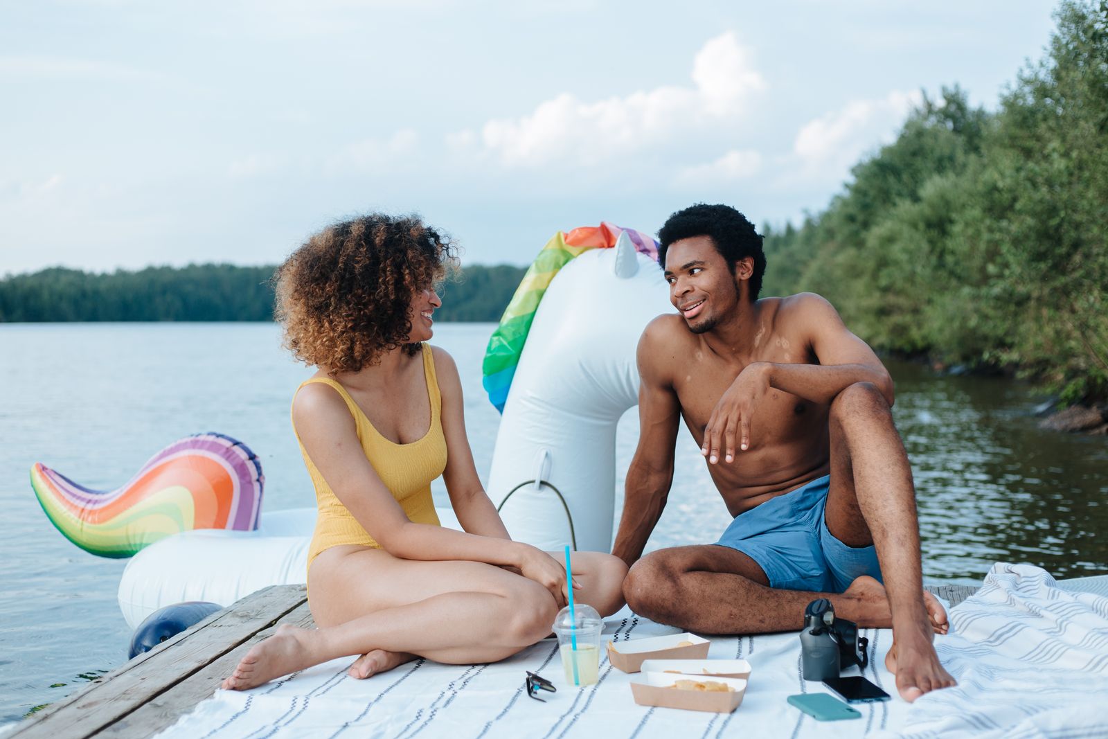 An affectionate couple enjoys a relaxing picnic with a scenic lakeside view.