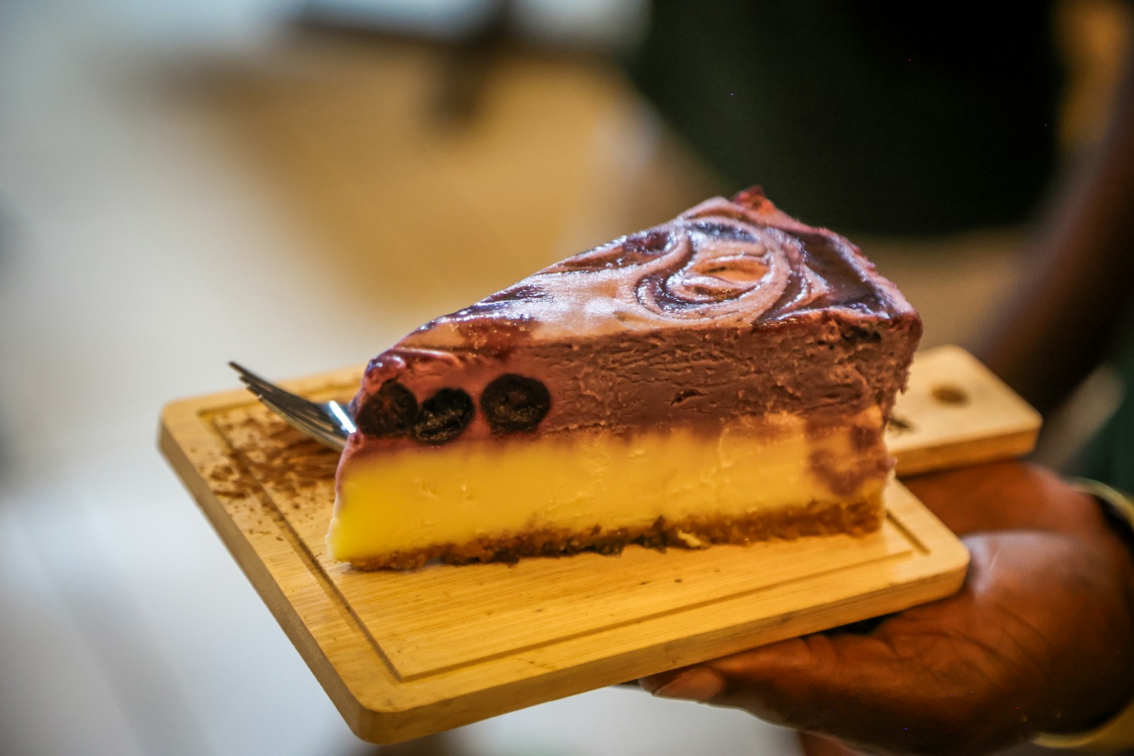 A slice of layered cheesecake with blueberries and swirl topping