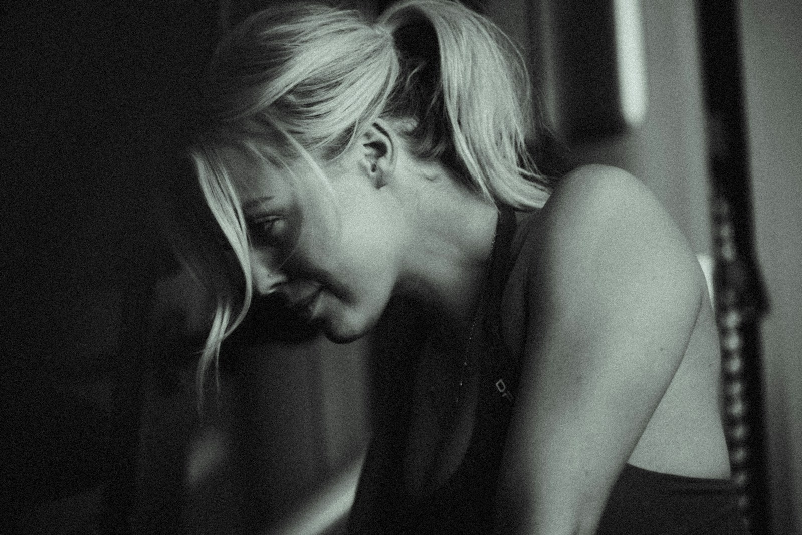 A black and white photo of a woman leaning against a wall