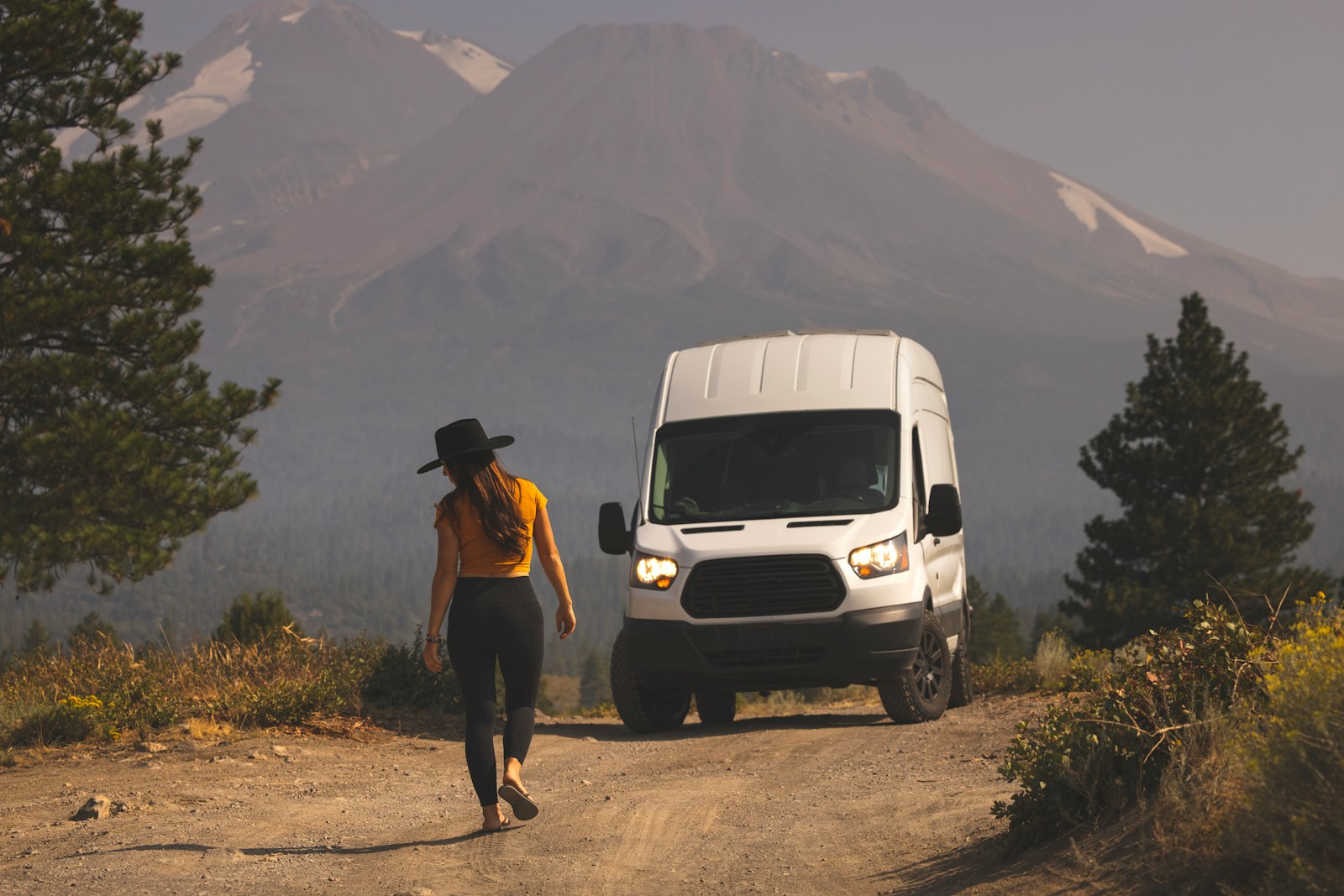 man in brown shirt standing beside white van during daytime