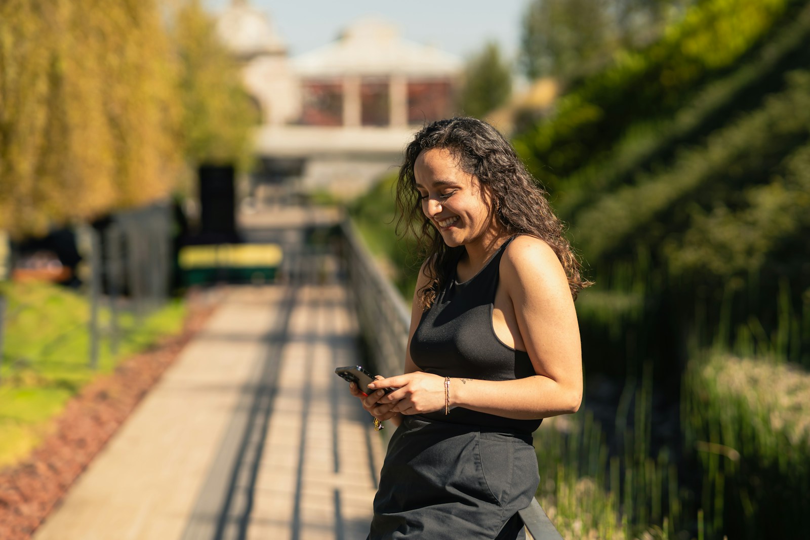 A woman in a black dress is looking at her cell phone