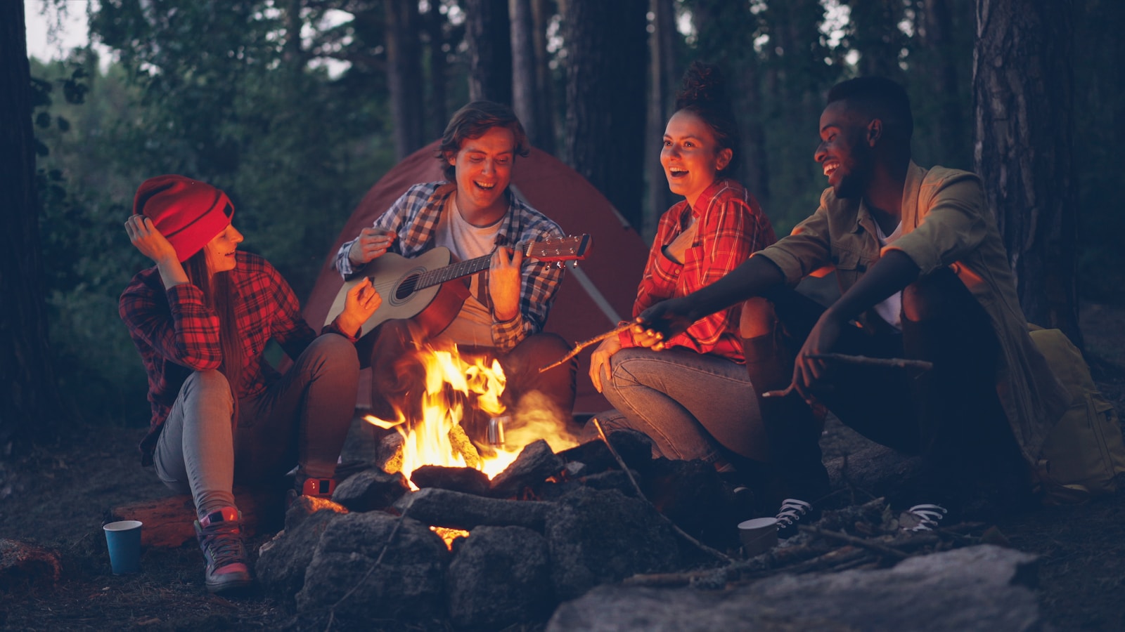 Friends laughing around a campfire in the woods