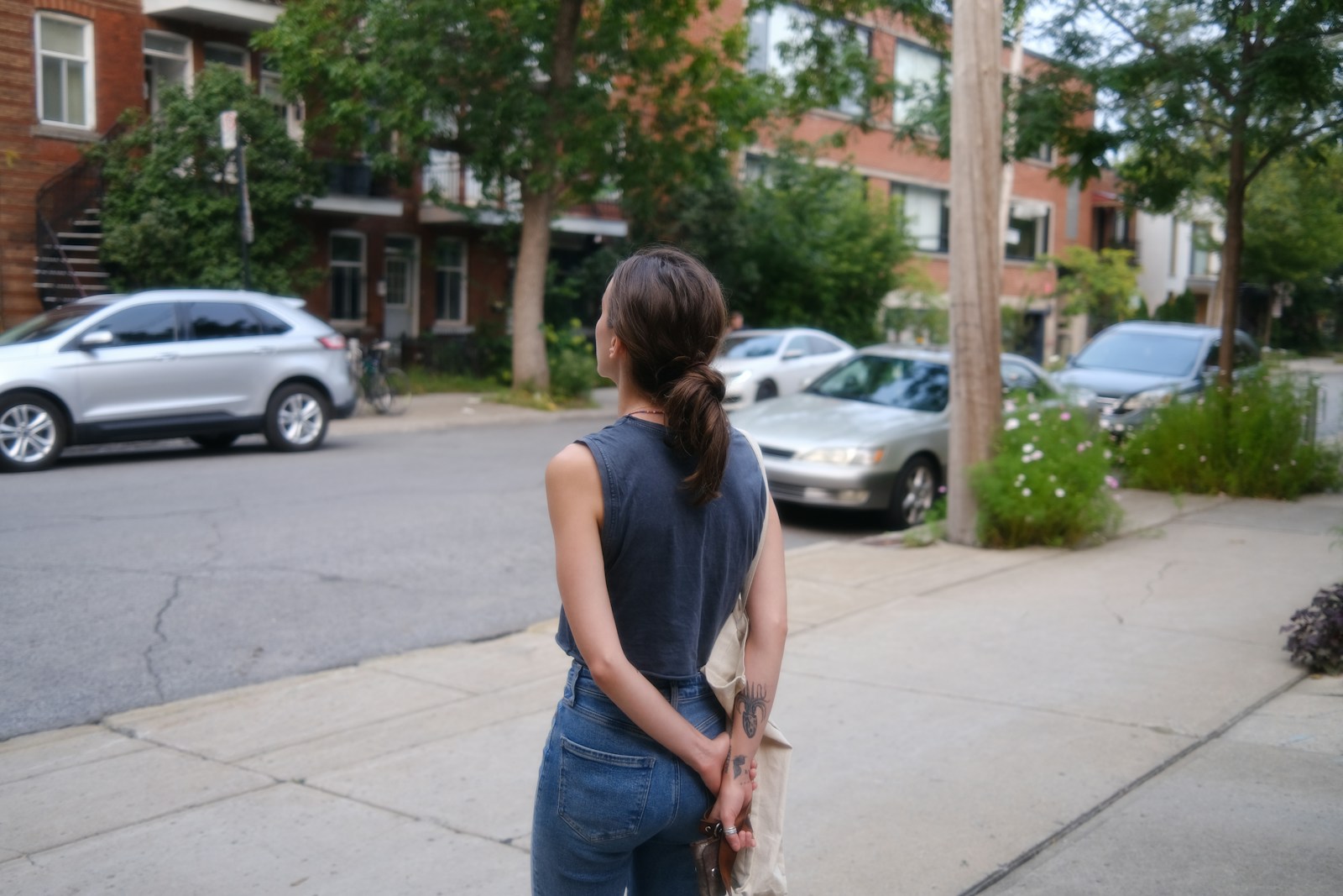 Woman standing on sidewalk with cars parked nearby