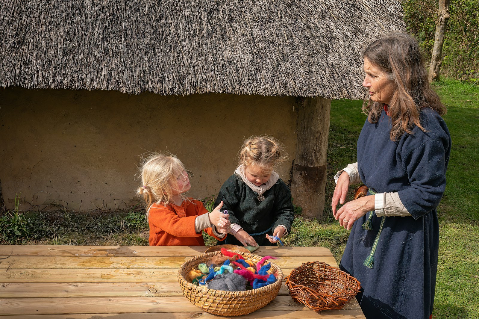 Woman teaching children historical crafts outdoors