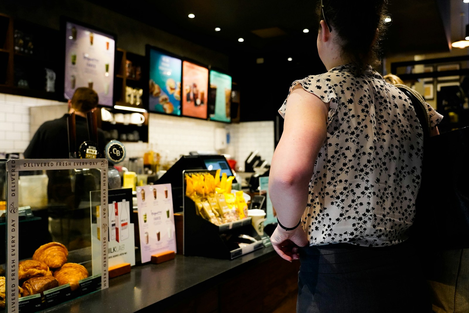 a woman standing in front of a counter filled with pastries